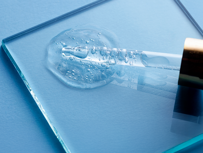 Glass dropper with clear liquid on a blue surface