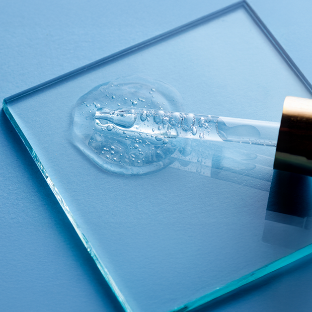 Glass dropper with clear liquid on a blue surface